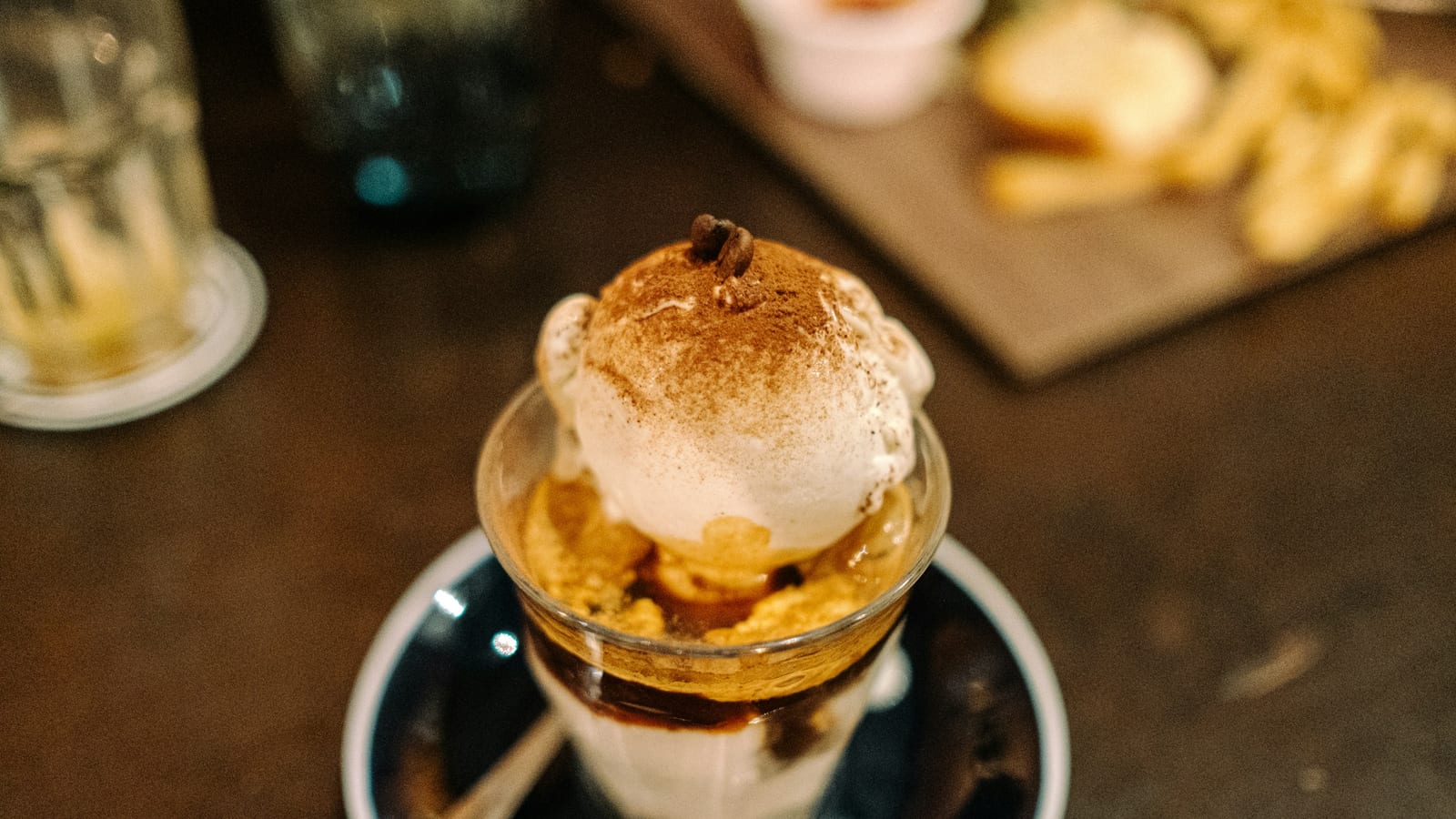 Bola de sorvete com cacau em pó e um grão de café sobre espresso, em um copinho de vidro
